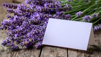 Fresh purple lavender flowers with blank white greeting card on rustic wooden background, aromatic herbs and empty paper note for message.