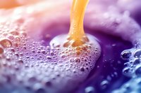 Colorful abstract liquid pouring with bubbles and foam creating vibrant purple orange gradient background for creative design projects.