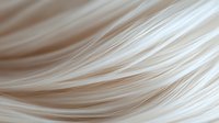 Soft flowing strands of platinum blonde hair create gentle waves and curves in macro view, showing silky smooth texture and natural shine in light beige tones.