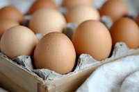 Fresh brown chicken eggs in cardboard carton with soft focus background, natural organic food concept for healthy eating and cooking ingredients.