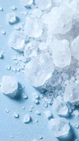 White sea salt crystals scattered on light blue surface, suitable for culinary, wellness, and spa industry applications.