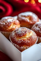 Fresh baked vanilla muffins dusted with powdered sugar in white paper cups and gift box, with festive red background and bokeh lights.