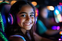Young Asian female gamer wearing purple gaming headphones smiles brightly in dark room with colorful bokeh lights, capturing joy and modern entertainment culture.