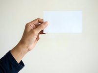 Male hand holding blank white card against neutral background, suitable for business presentations, marketing mockups, and promotional material displays.