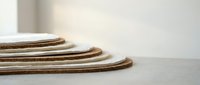 Stack of natural cork yoga mats rolled up on wooden floor in minimalist studio space for fitness and wellness practice.