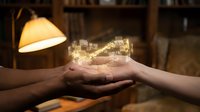 Cupped hands holding glowing digital cityscape hologram in warm indoor setting with lamp creating magical technology concept for future urban planning.
