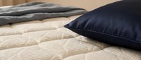 Comfortable bedroom setup with navy blue pillow on quilted beige bedding, featuring soft textures and neutral tones for home decor and interior design projects.