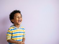 Young boy with dark curly hair and medium brown skin tone wearing yellow and blue striped shirt, smiling and looking upward against purple background for children's advertising and lifestyle content.