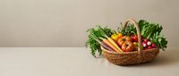Fresh organic vegetables in wicker basket including carrots, radishes, leafy greens and herbs on neutral background for healthy cooking and nutrition.