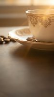 Elegant vintage porcelain teacup and saucer with ornate golden pattern on wooden table in warm sunlight for luxury dining and hospitality concepts.