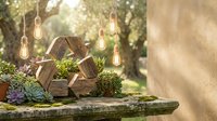 Wooden recycle symbol surrounded by succulents and vintage Edison bulbs in a sunlit garden, promoting sustainability and eco-friendly living concepts.