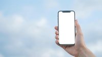 Hand holding smartphone with blank white screen against soft cloudy sky background, mockup for app or website display.