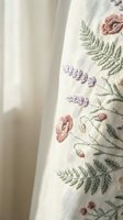 Delicate floral embroidery on cream linen fabric featuring pink poppies, purple lavender and green ferns for home decor and textile design projects.