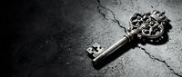Ornate vintage skeleton key with decorative baroque handle lying on cracked concrete surface in dramatic black and white lighting for mystery concepts.
