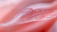 Close-up macro shot of pink lip gloss or lipstick swatch on skin showing smooth creamy texture and natural shine for cosmetic and beauty applications.