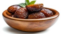 Sweet dried dates in wooden bowl with fresh mint leaves, healthy natural snack for energy boost and culinary use.
