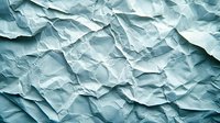 Crumpled paper texture in light blue tones creates dramatic shadows and depth. Abstract background with wrinkled surface shows natural folds and creases.