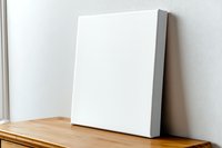 Blank white square canvas mockup leaning on wall on wooden shelf. Clean minimal art presentation for gallery, home decor and artists portfolio display.