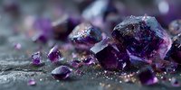Purple amethyst crystal clusters with raw gemstones on dark textured surface, illuminated with soft light highlighting facets and sparkle.