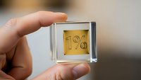 Hand holding transparent glass cube with golden 1% percentage symbol inside, representing low interest rates, minimal fees or exclusive membership benefits.