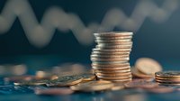 Stack of silver coins on blue background with blurred financial chart, representing investment growth, savings and wealth management concept.