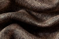 Close-up macro shot of brown linen fabric texture with natural fibers and weave pattern showing waves and folds in soft lighting for textile design background.