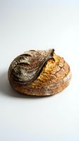 Artisan sourdough bread loaf with golden crust and rustic scoring isolated on white background for bakery and food design projects.