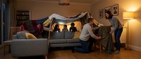 Family building blanket fort in cozy living room with warm lighting, parents and children creating indoor tent for fun bonding activity at home.