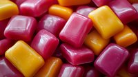 Colorful assorted fruit gummy candies in pink, red, orange and yellow scattered together. Sweet chewy confectionery treats for snacking and desserts.