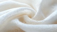 Soft white cotton fabric with gentle folds and waves creating an elegant textural background pattern, suitable for fashion, interior design, and lifestyle projects.