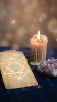 Mystical tarot card with glowing geometric symbol beside burning candle and amethyst crystals on dark blue velvet surface with magical bokeh lights.