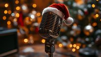 Vintage microphone wearing Santa hat against blurred Christmas tree lights and bokeh background creates festive holiday music atmosphere.