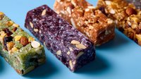 Colorful homemade granola bars with nuts, dried fruits and seeds on blue background. Healthy snacks rich in protein and natural ingredients for balanced nutrition.