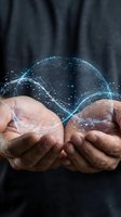 Businessman cupping hands with glowing digital energy waves and sparkling particles floating above palms representing innovation and futuristic technology concepts.