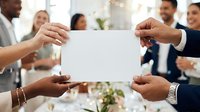Diverse group of business professionals holding blank white card together at corporate meeting or team building event for announcement or message.