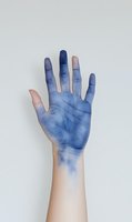 Human hand with blue paint or ink stains isolated on white background for creative art and design projects.
