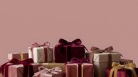 Luxury gift boxes wrapped in burgundy, rose gold, and neutral ribbons arranged on soft pink background for holiday celebrations.