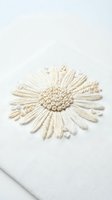 Cream colored embroidered daisy flower on white linen fabric showcasing detailed needlework and textile artistry for crafting and sewing projects.