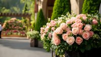 Pink roses and baby's breath arranged in rustic planter against blurred garden background, creating romantic outdoor wedding or event decoration atmosphere.