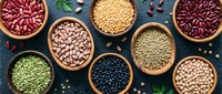 Assorted legumes and beans in wooden bowls on dark background. Variety of protein-rich pulses including lentils, chickpeas, kidney beans for healthy cooking.
