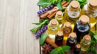 Natural essential oils in glass bottles with herbs and spices on wooden background for aromatherapy, wellness and holistic healing treatments.