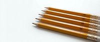Yellow wooden pencils with pink erasers arranged in row on white background for office and school supplies design projects.