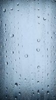 Water droplets on glass surface creating natural condensation pattern for backgrounds and textures in blue tones.