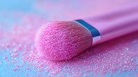 Pink makeup brush with scattered shimmer powder on pastel background, close-up macro shot showing soft bristles and metallic handle for cosmetics and beauty content.