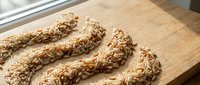 Rows of granola bars or cereal bars with oats and nuts arranged on wooden surface near window with natural light.