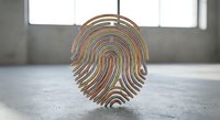 Metallic fingerprint sculpture with golden bronze finish standing on concrete floor in modern minimalist interior space for security and identity concepts.