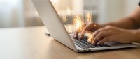 Hands typing on laptop with glowing lightbulb icons representing innovation, creativity and bright ideas for business technology and digital solutions.