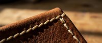 Brown leather wallet corner with detailed hand-stitched seams showcasing traditional craftsmanship and quality materials for luxury accessories and fashion.