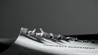 Torn contract agreement document with metal chain symbolizing broken business deal or legal dispute in monochrome style for corporate presentations.