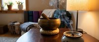 Tibetan singing bowl with aromatic smoke creating peaceful meditation atmosphere in cozy living room with warm lighting and home decor elements.